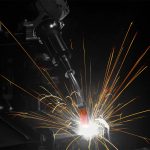 Closeup of through-arm robotic MIG gun with sparks