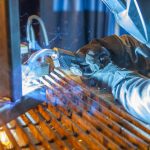 Welder welding with a Bernard semi-automatic MIG gun with T-series handle.