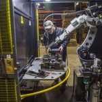 Robotic operator with a teach pendant by a robotic MIG welding cell