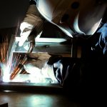 Closeup of welding operator welding on a square part on a table